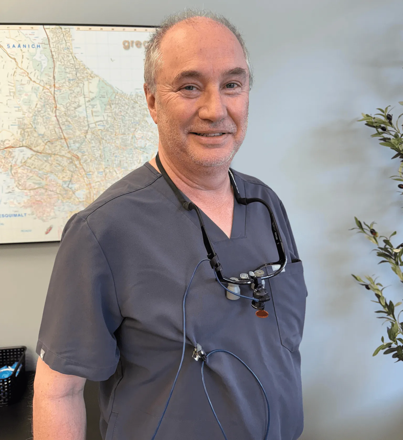 Dr. Paul Henn in grey scrubs with dental loupes around his neck